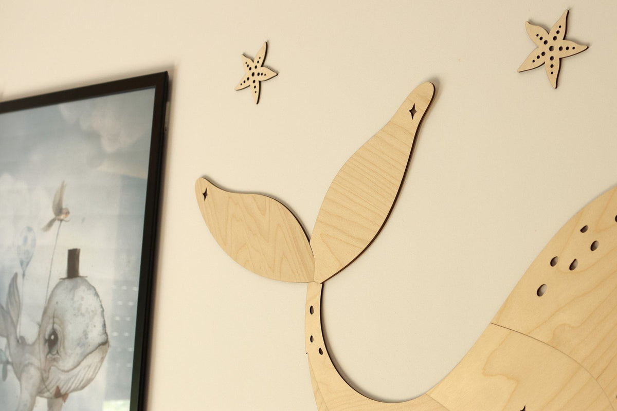 3. Close-up of wooden whale tail and starfish wall decorations on a beige wall