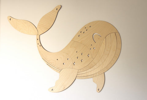 2. Wooden whale wall decoration on a plain beige wall showing detailed carving