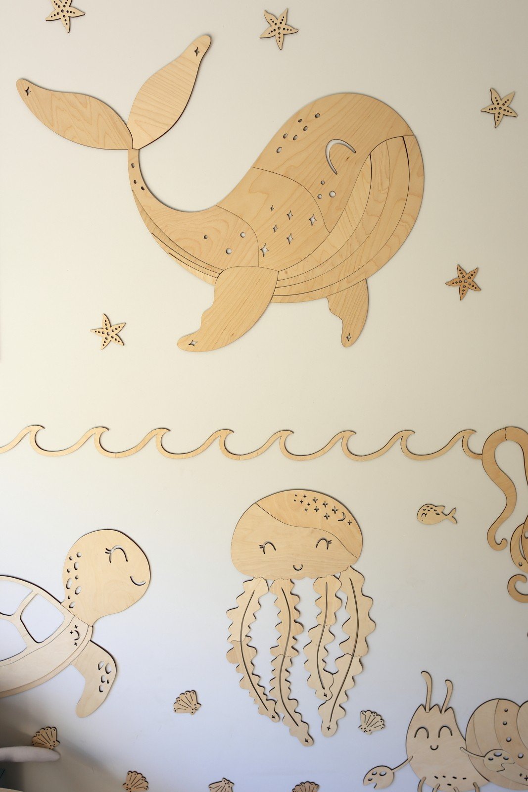 4. Wooden whale wall decoration with sea-themed extras like jellyfish and turtle on a beige wall
