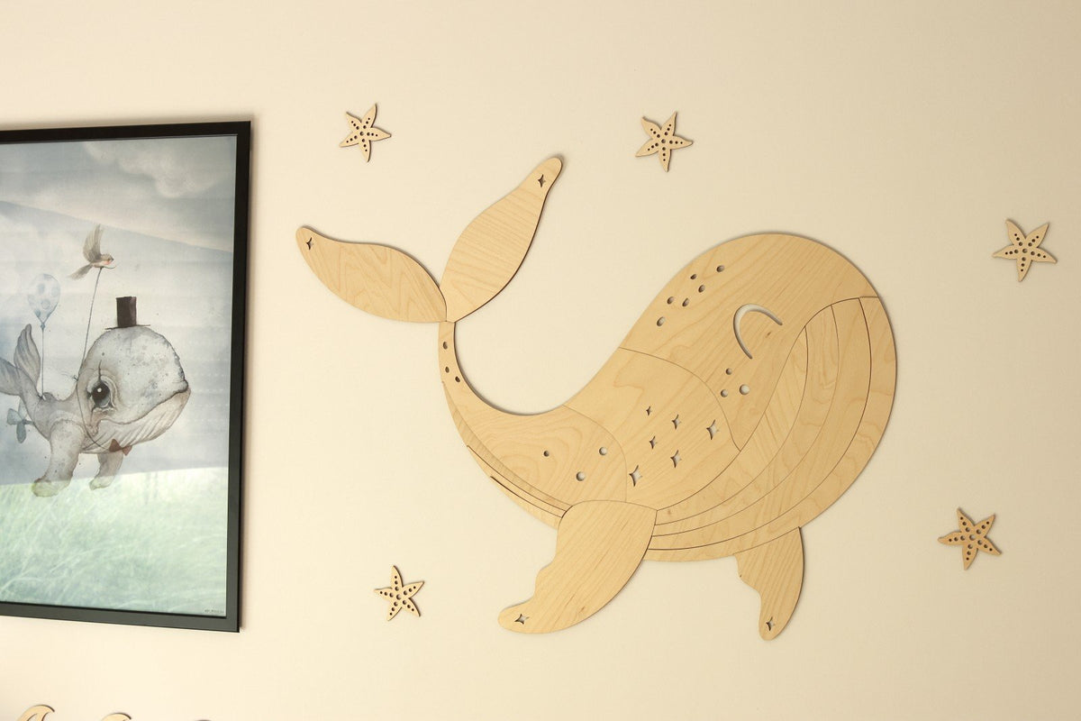1. Wooden whale wall decoration with starfish accents on a beige wall next to a framed ocean-themed picture