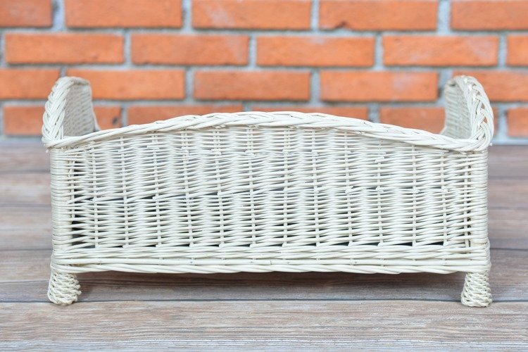2. Back view of whitewashed wicker pet bed showing woven design on wooden floor with brick wall background