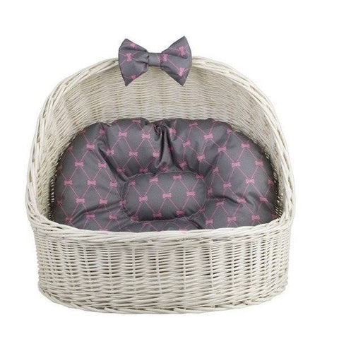 1. Whitewashed wicker pet house with grey cushion featuring pink pattern and decorative bow, front view