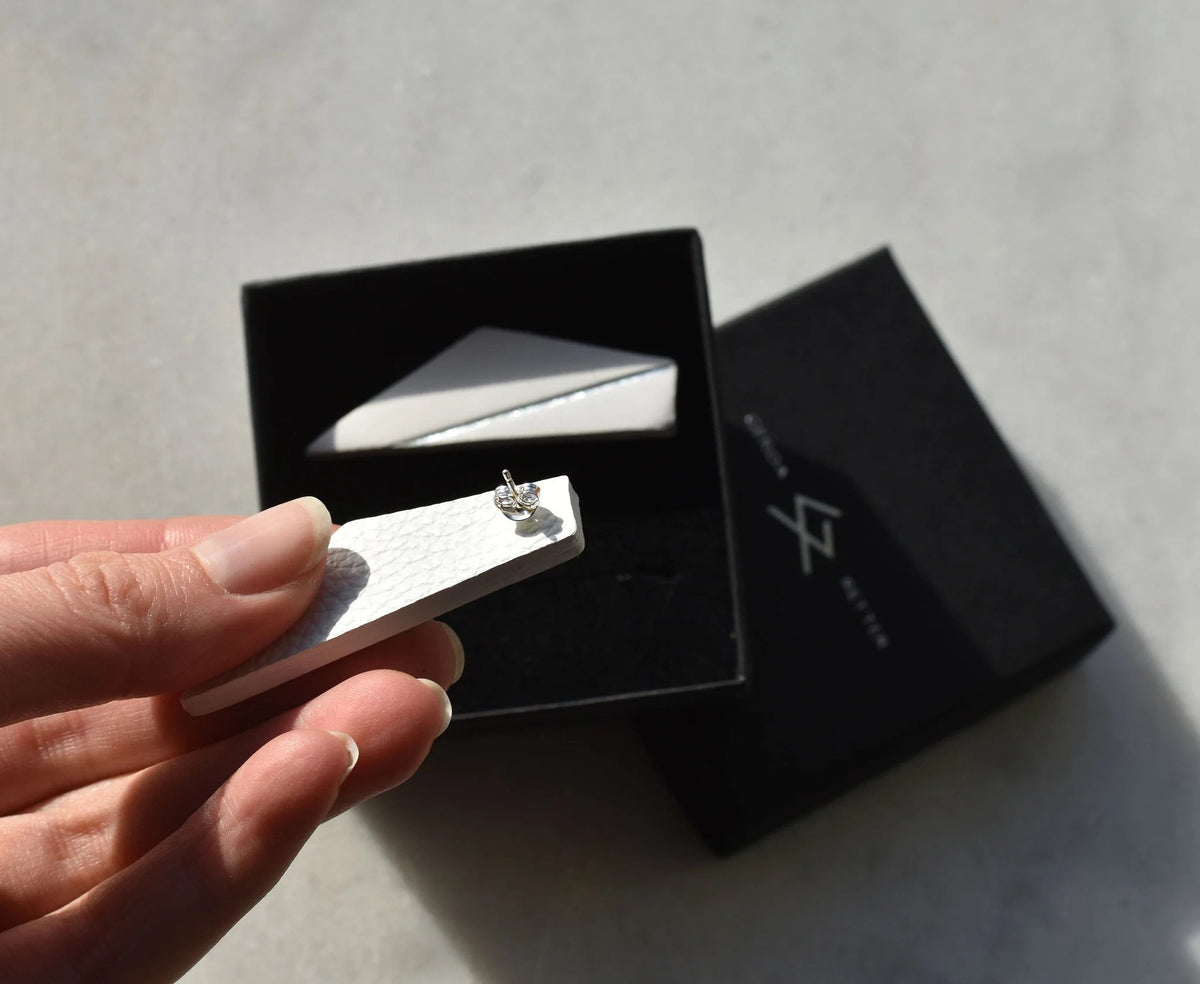 4. Close-up of white Gerda Retter Design Short Wings Earring with silver backing, held in hand