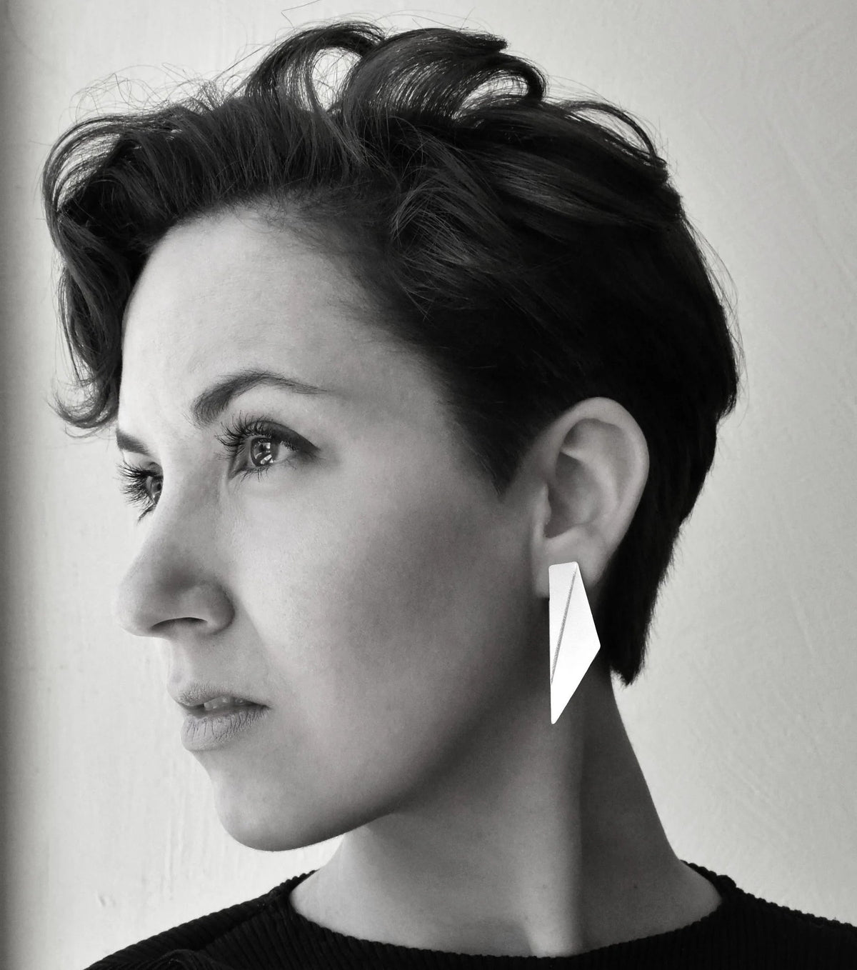 1. Woman wearing Gerda Retter Design Short Wings Earrings in white, showcasing geometric elegance