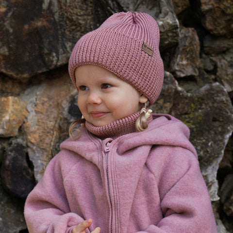 4. Child in blush merino wool hat and neck warmer against stone wall