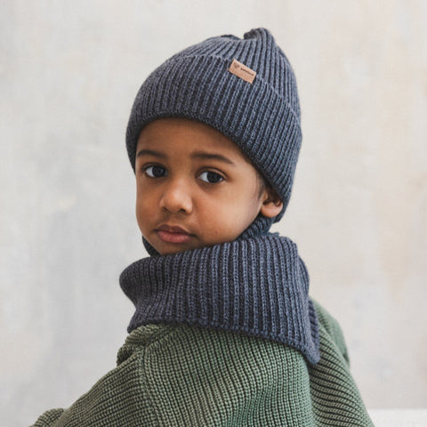 4. Child in graphite merino wool hat and scarf, indoors, wearing green sweater