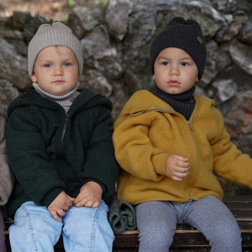 6. Two children sitting on bench, one in graphite merino wool hat, outdoors