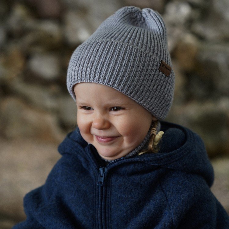 4. Child wearing grey merino wool hat outdoors, smiling in blue jacket