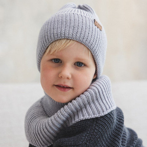 1. Child wearing grey merino wool hat with matching scarf indoors, smiling