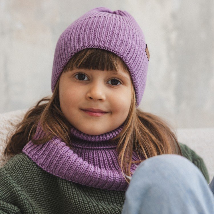 2. Girl in lilac merino wool hat and scarf sitting on couch with light background