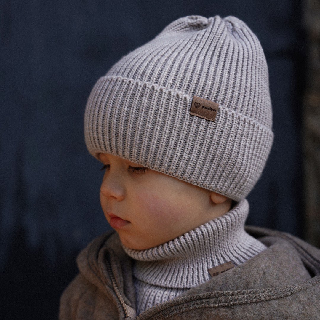 7. Child wearing Patulove oat-colored merino wool hat and coat, looking to the side outdoors