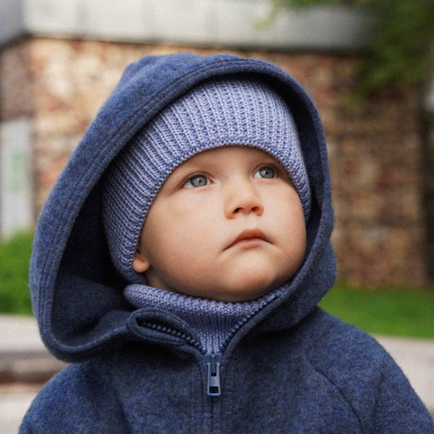 1. Child in sky blue merino wool hat and neck warmer, wearing hooded jacket, looking upwards outdoors