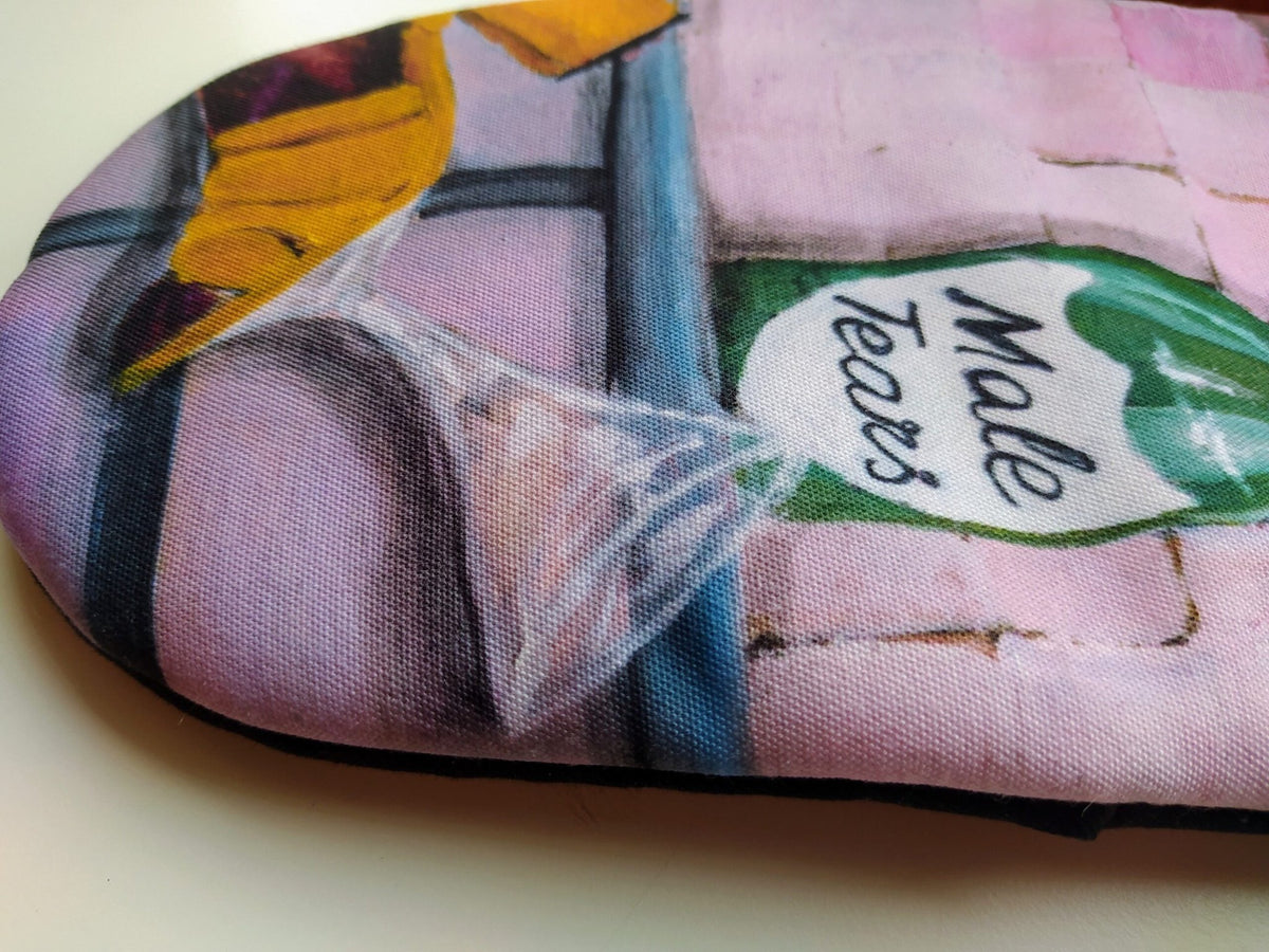 6. Close-up of Katrin Valgemäe oven mitt showing 'Male Tears' bottle and kitchen elements
