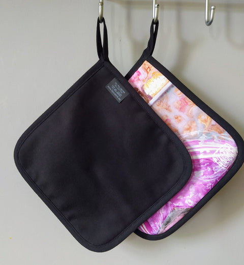 2. Back view of Katrin Valgemäe pot holder set, showing plain black side and pop art design side with hanging loops