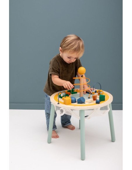 1. Toddler playing with Trixie Baby Wooden Educational Table featuring toy car track, gears, and animal figurines in a playroom setting