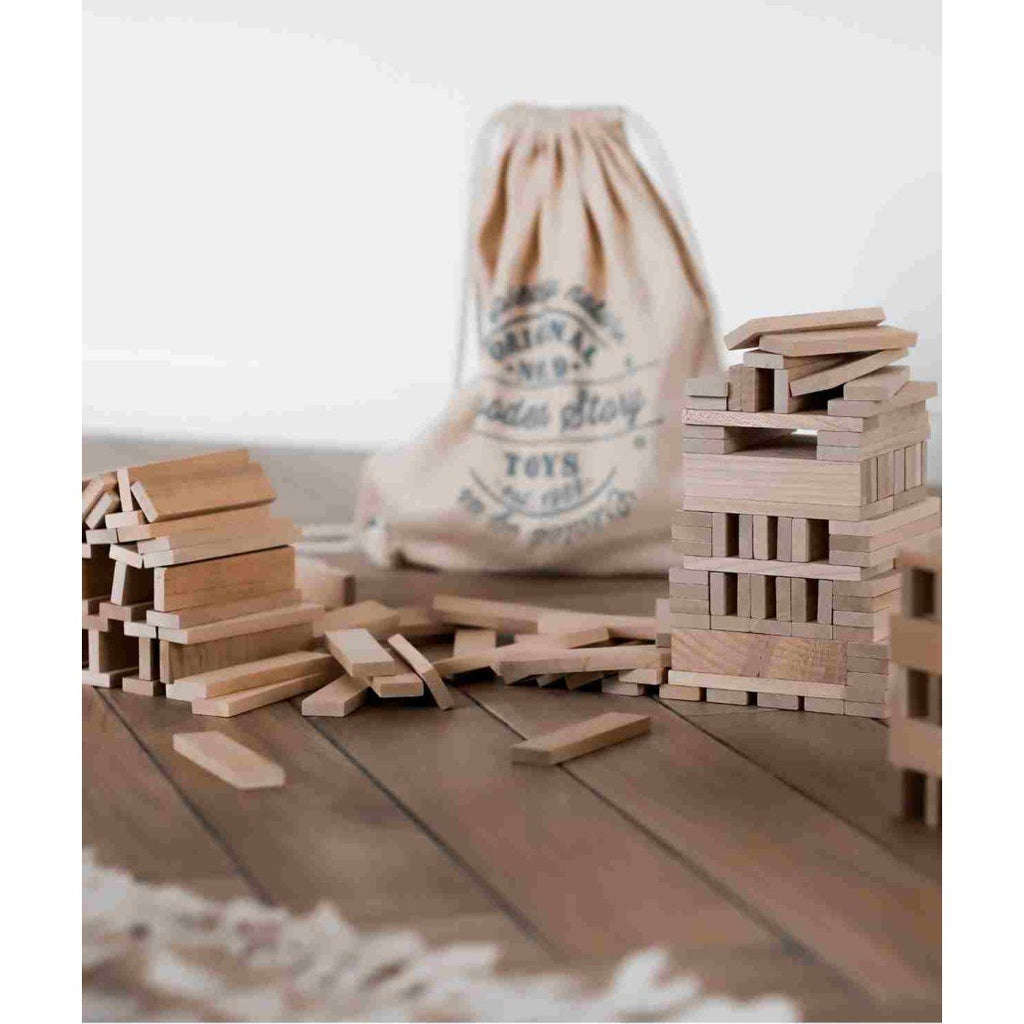 4. Flat lay of Wooden Story blocks scattered on floor with branded bag in background, showing natural wood tones