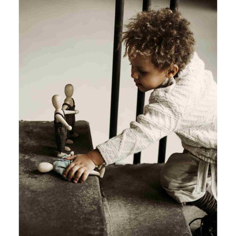 1. Child playing with two wooden beech dolls on a carpeted staircase
