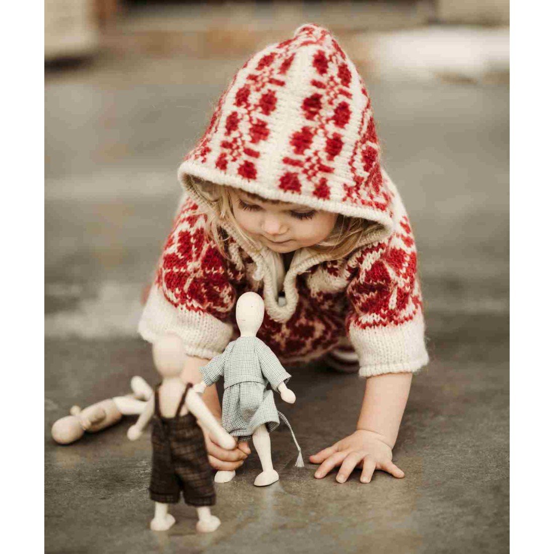 13. Child in red patterned sweater crawling towards Wooden Story beech dolls on floor
