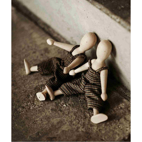 1. Two wooden beech dolls with pants sitting against a wall on a textured surface