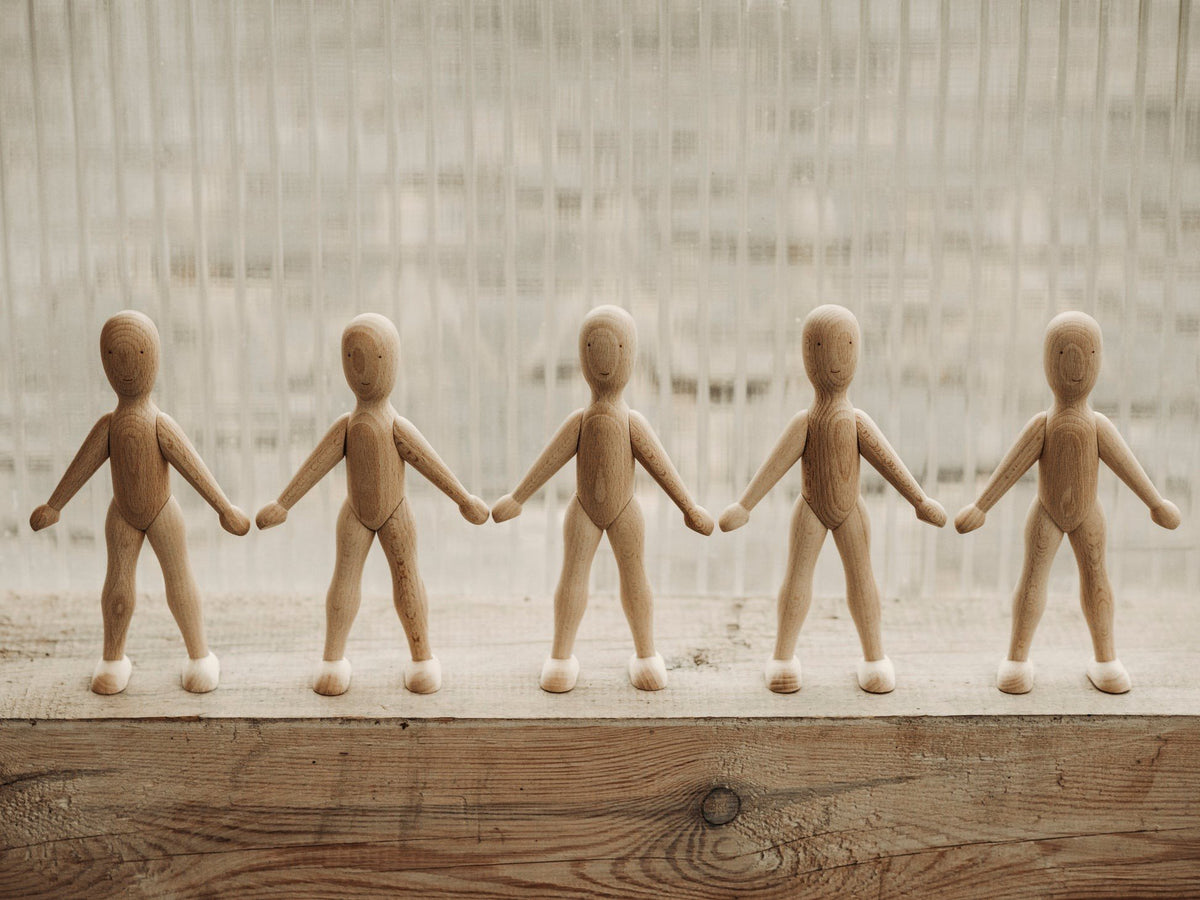 1. Five wooden beech dolls holding hands on a wooden surface