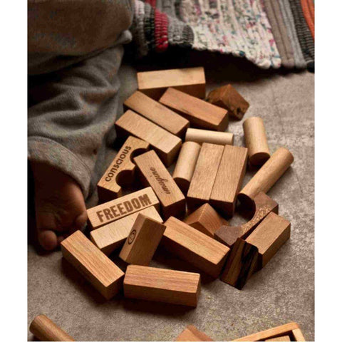 3. Close-up of Wooden Story natural wooden blocks with engraved words like 'FREEDOM' and 'CONSCIOUS', highlighting smooth texture and eco-friendly design