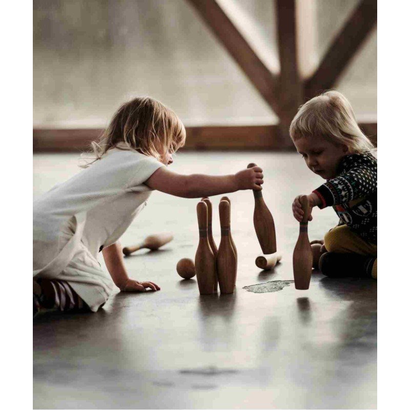 1. Two children playing with wooden bowling pins on a wooden floor indoors