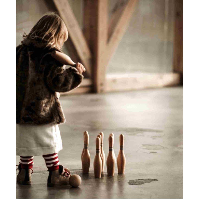 1. Child in striped leggings setting up wooden bowling pins on a wooden floor