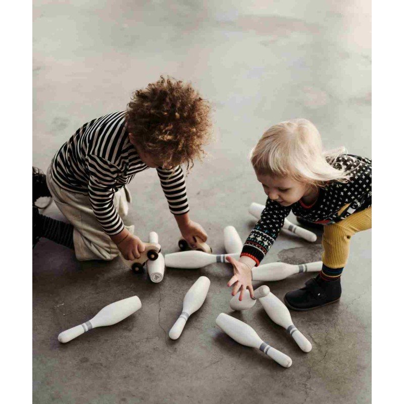 1. Two children playing with scattered wooden bowling pins on a concrete floor