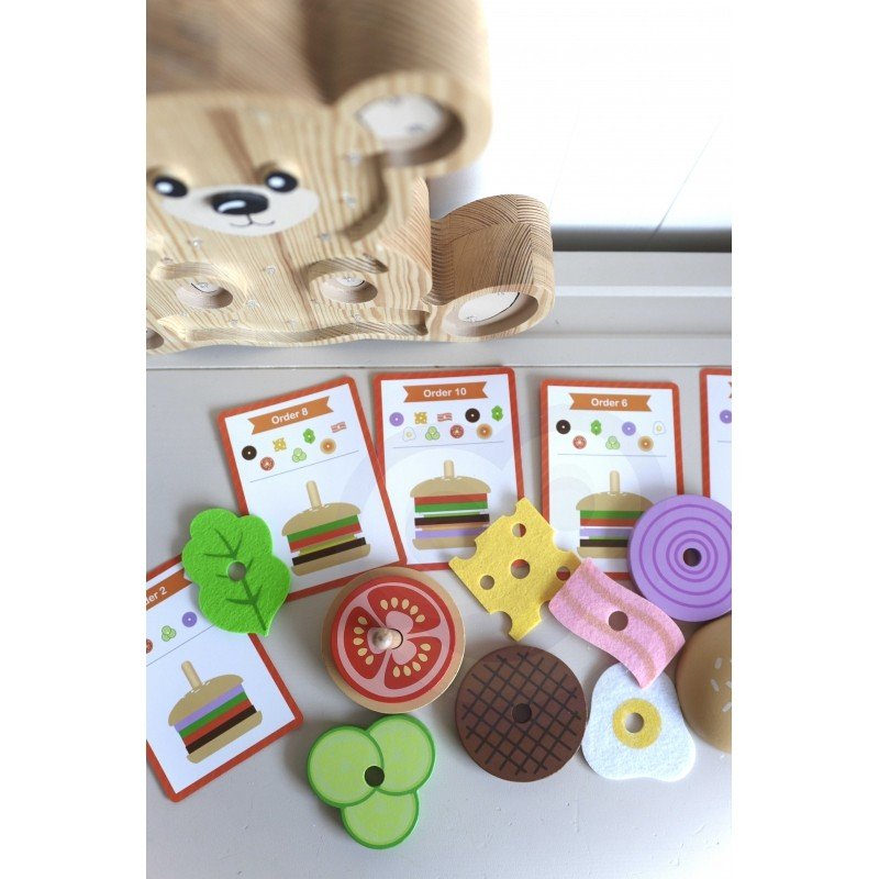 6. Assorted wooden burger puzzle pieces and recipe cards displayed on a white surface with a wooden bear decoration