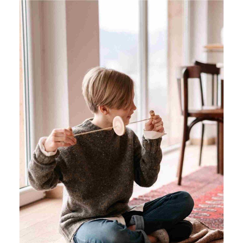 1. Child in grey sweater playing with Wooden Buzz Spinner in a bright room