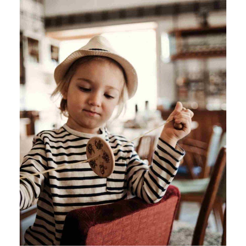 1. Child in striped shirt and hat using Wooden Buzz Spinner in a cozy room