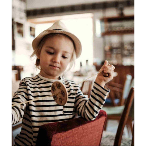 1. Child in striped shirt and hat using Wooden Buzz Spinner in a cozy room