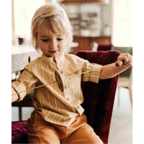 1. Child in striped shirt playing with Wooden Buzz Spinner indoors