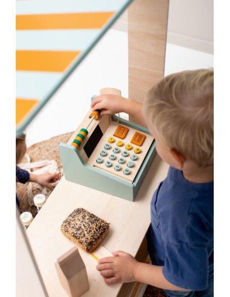 6. Child using wooden cash register in play setting with toy food items
