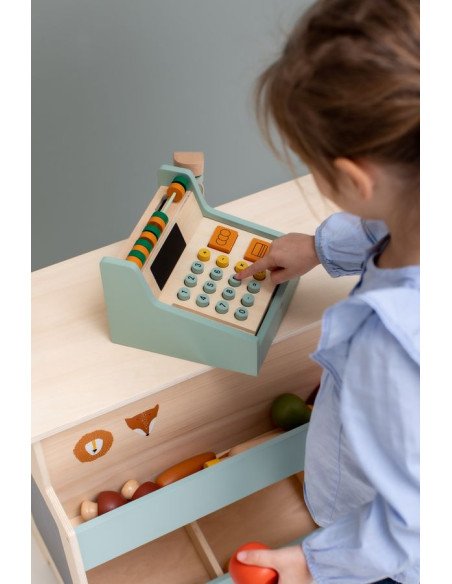 9. Child interacting with wooden cash register on a play store counter