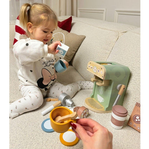 1. Child playing with Woopie Green barista set on sofa with coffee machine and accessories