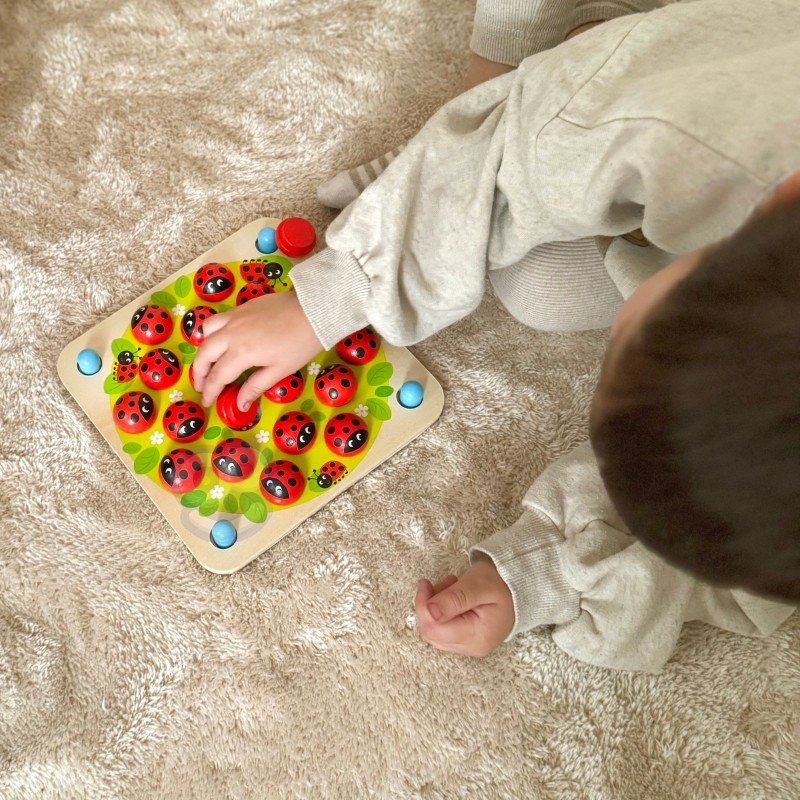 10. Child interacting with Woopie Let's Go Green ladybug memory puzzle on a soft surface