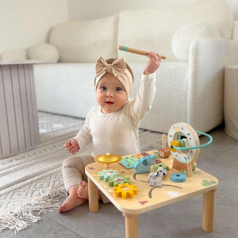12. Toddler enthusiastically playing with Woopie 5-in-1 activity table on grey carpet