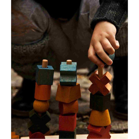 3. Close-up of a child's hand stacking colorful wooden blocks on a post, enhancing hand-eye coordination