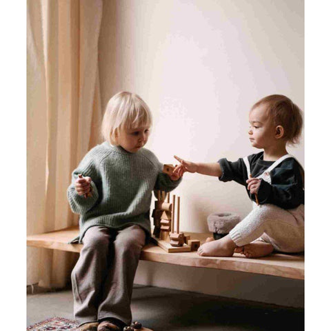 1. Two children interacting with Wooden Fence Puzzle by Wooden Story on a wooden bench