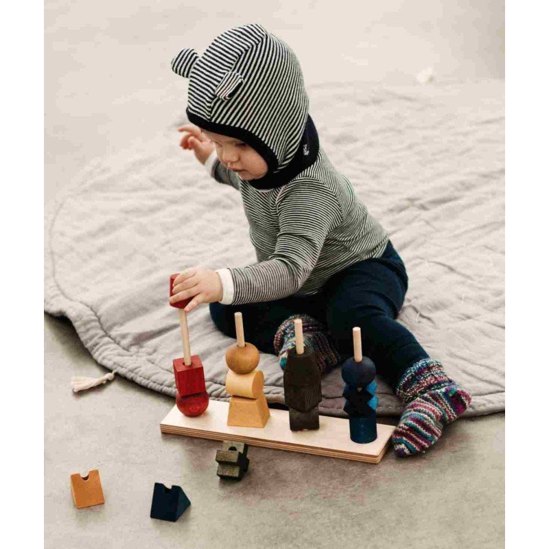 1. Toddler sitting on a mat assembling colorful wooden fence puzzle, wearing striped outfit and socks