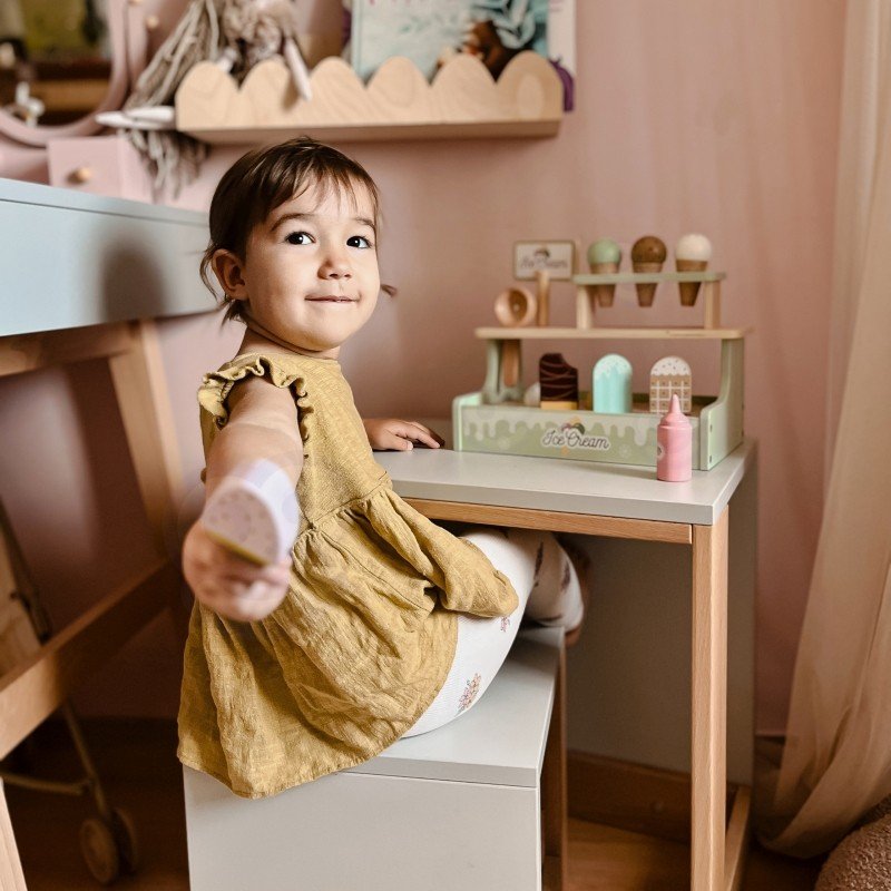 10. Girl in yellow dress sitting at table with Woopie Green ice cream stand in a playroom