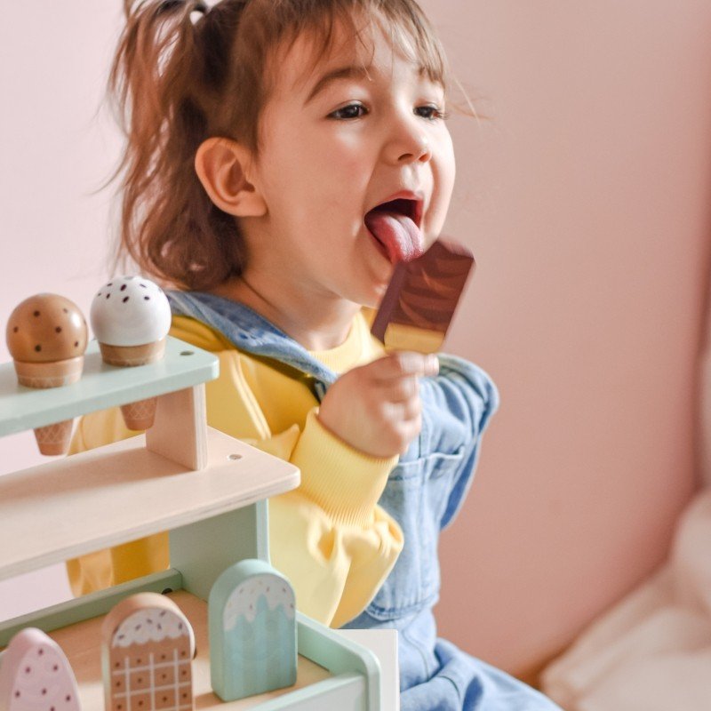 9. Girl licking chocolate popsicle while playing with Woopie Green ice cream stand