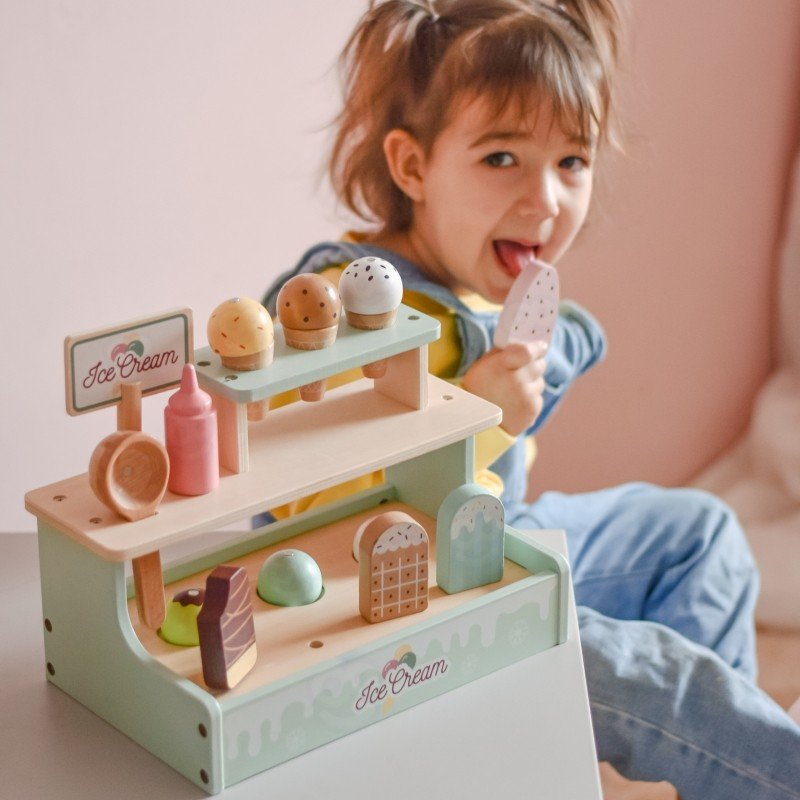 6. Girl enjoying popsicle while playing with Woopie Green ice cream stand in a pink room