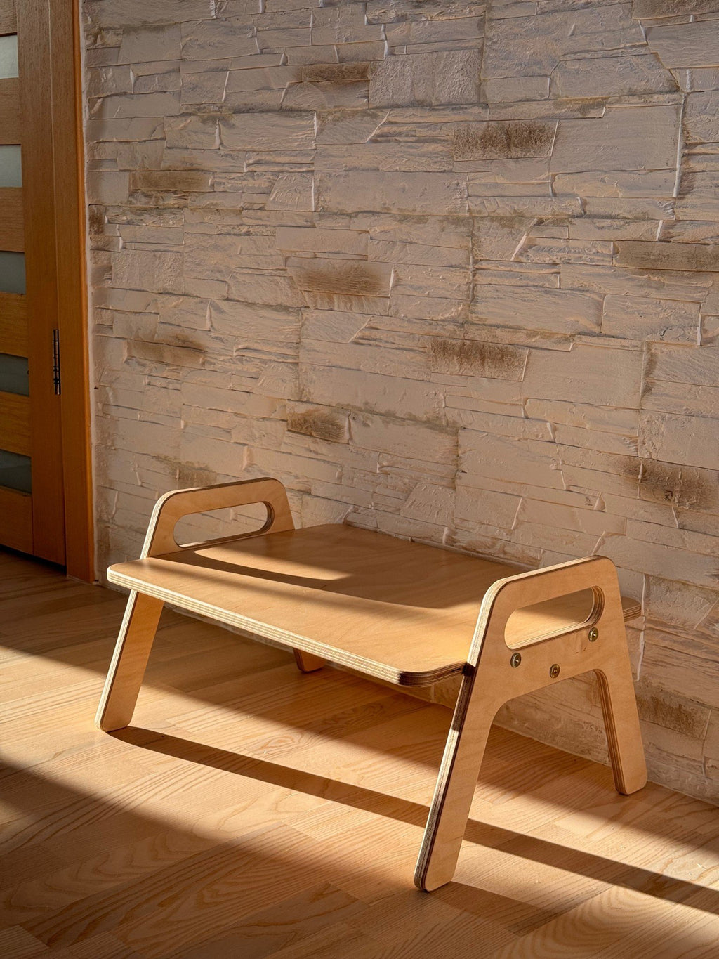 1. Wooden kids floor table with natural wood finish in a sunlit room against a textured wall, showcasing minimalist design and smooth edges