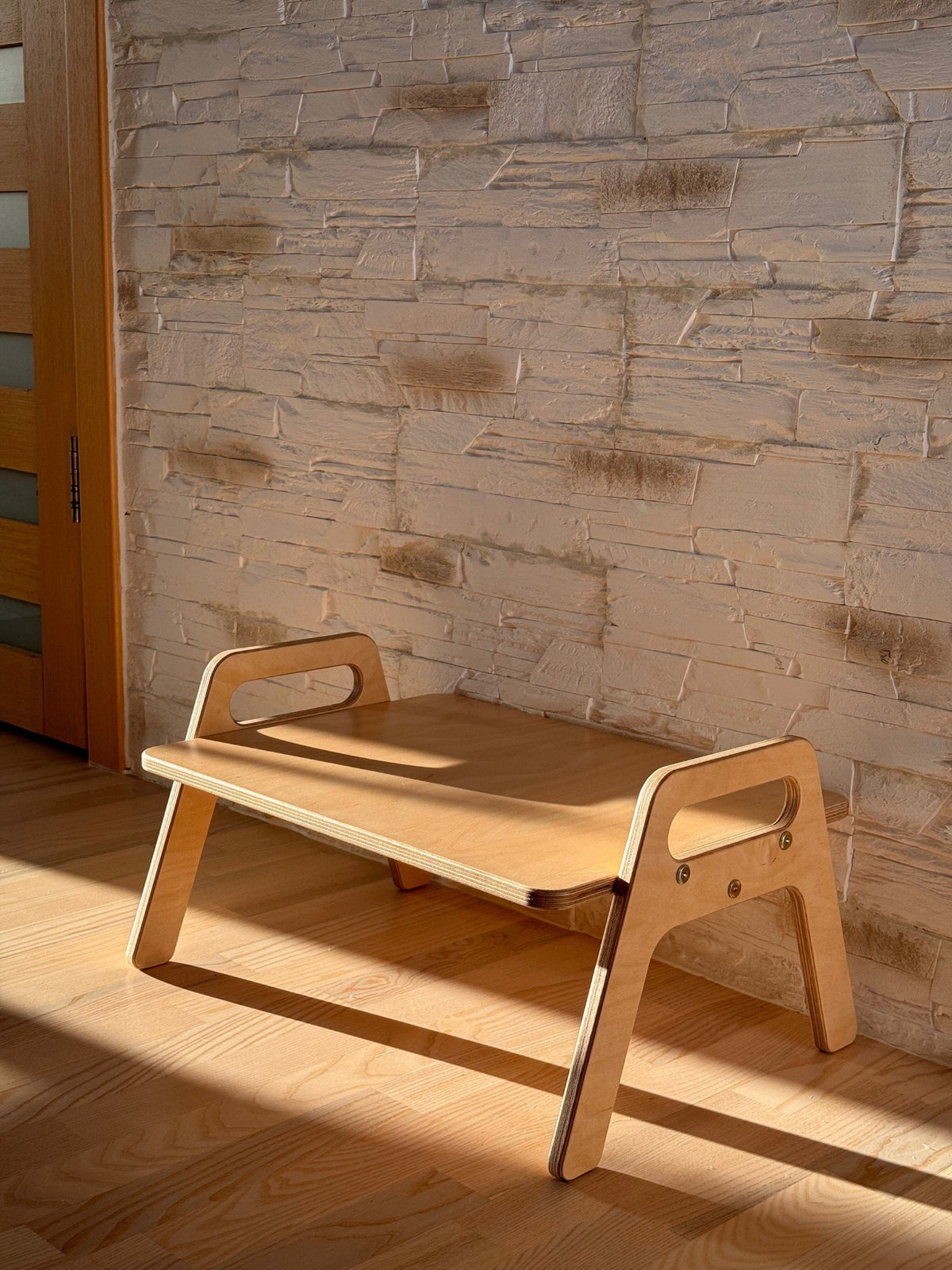1. Wooden kids floor table with natural wood finish in a sunlit room against a textured wall, showcasing minimalist design and smooth edges