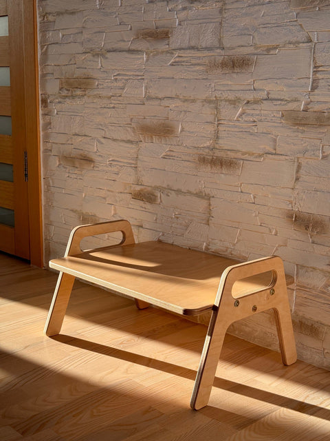 1. Wooden kids floor table with natural wood finish in a sunlit room against a textured wall, showcasing minimalist design and smooth edges