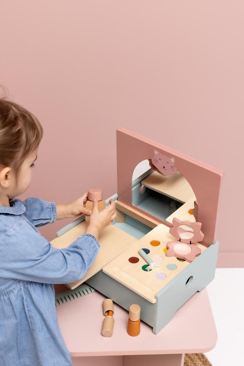 4. Child interacting with Trixie Baby Wooden Make-Up Table, showing storage and accessories in a pastel pink setting