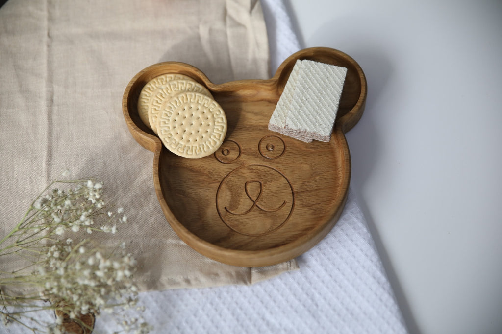 4. Top view of wooden bear-shaped plate with snacks, on beige and white textured cloth