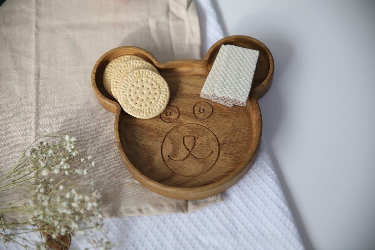 4. Top view of wooden bear-shaped plate with snacks, on beige and white textured cloth